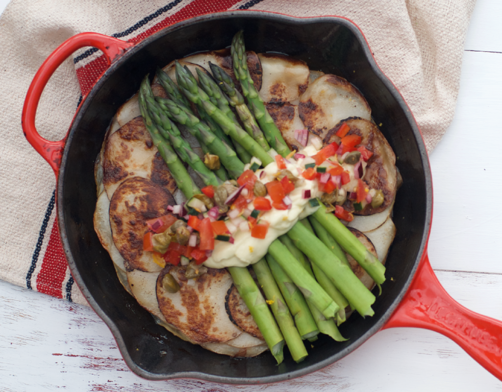 Red cast iron pan with potato galette, asparagus, aquafaba mayo and a salsa