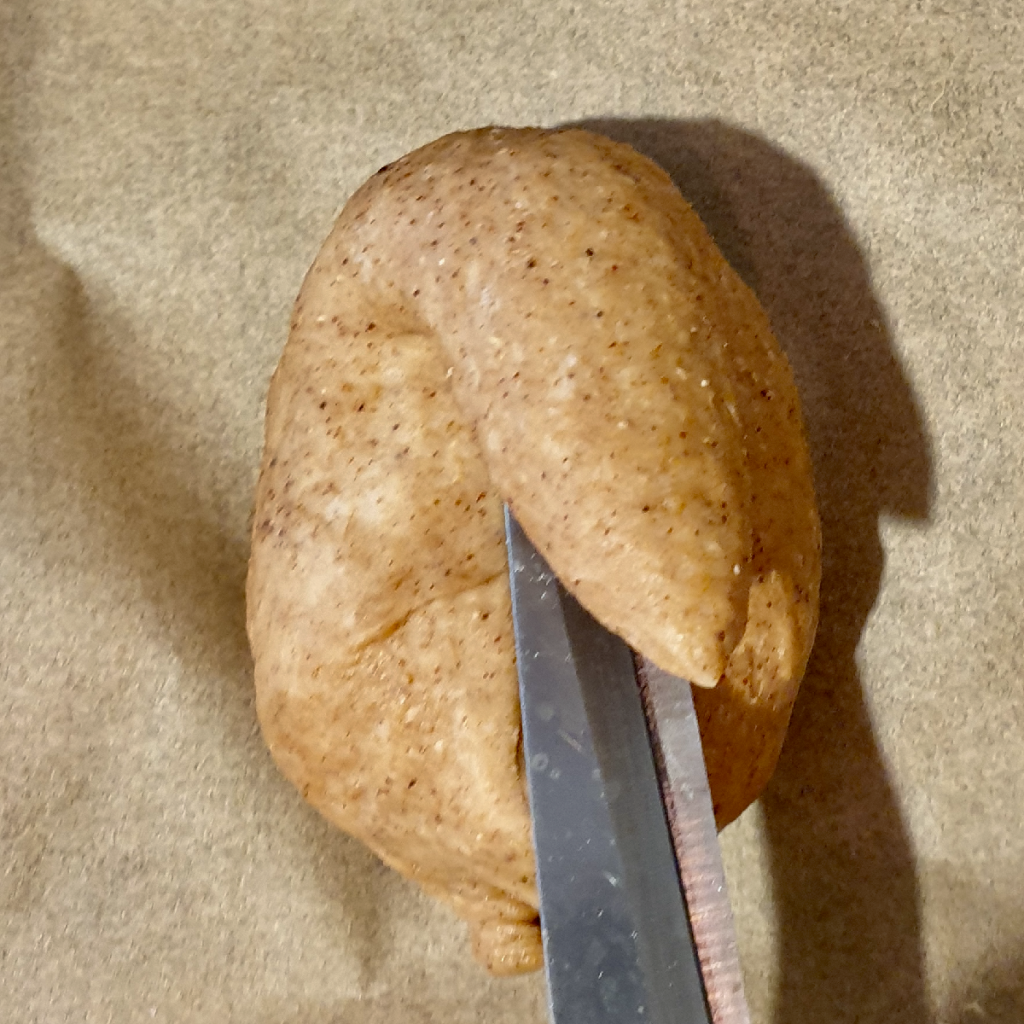 Cutting through the top of the small vegan Easter loaf to make bunny ears