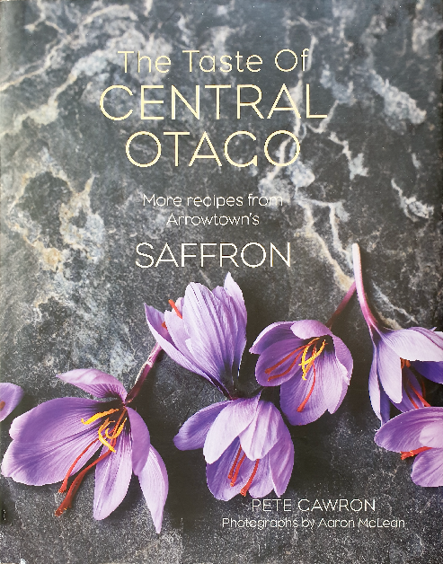 The cover of the cookbook displays the title "The Taste of CENTRAL OTAGO" in elegant, serif font against a dark, marble-like background. Below the main title, it reads "More recipes from Arrowtown's SAFFRON" in a smaller type, highlighting the source of the recipes. The author's name, "PETE CAWRON," is given prominence at the bottom, with a credit for "Photographs by Aaron McLean" just below. The cover is adorned with striking images of saffron crocus flowers, featuring rich purple petals and vivid orange-red stigmas, which are the parts of the flower used as the saffron spice.