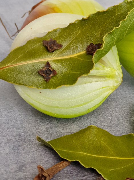 onion piqué, which is typically used to infuse flavor into soups, stocks, and sauces. The onion is halved and studded with cloves and bay leaves