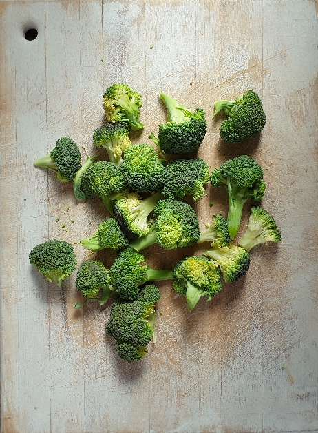 Broccoli florets on a rustic distressed white cutting board