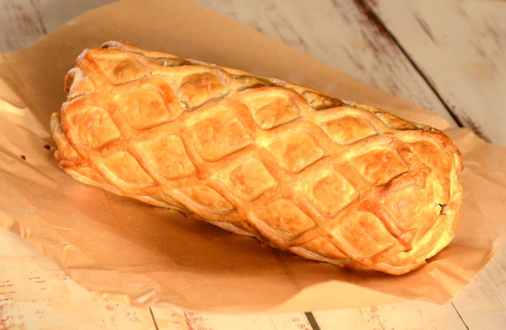 A vegan Haggis Wellington wrapped in golden pastry with a layer of lattice cut pastry.